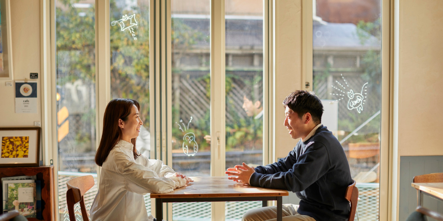 カフェの落ち着いた空間で、楽しそうにプロフィールや趣味について話すマッチングアプリで出会った男女。