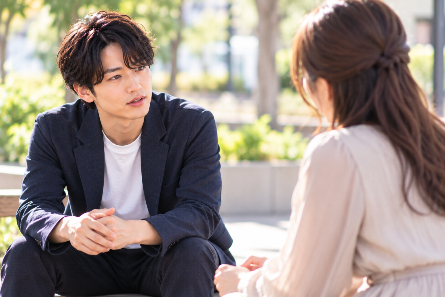 婚活中の男性が公園で交際相手の女性と向き合い、結婚前に伝えておきたい家族の事情について真剣に話している様子。
